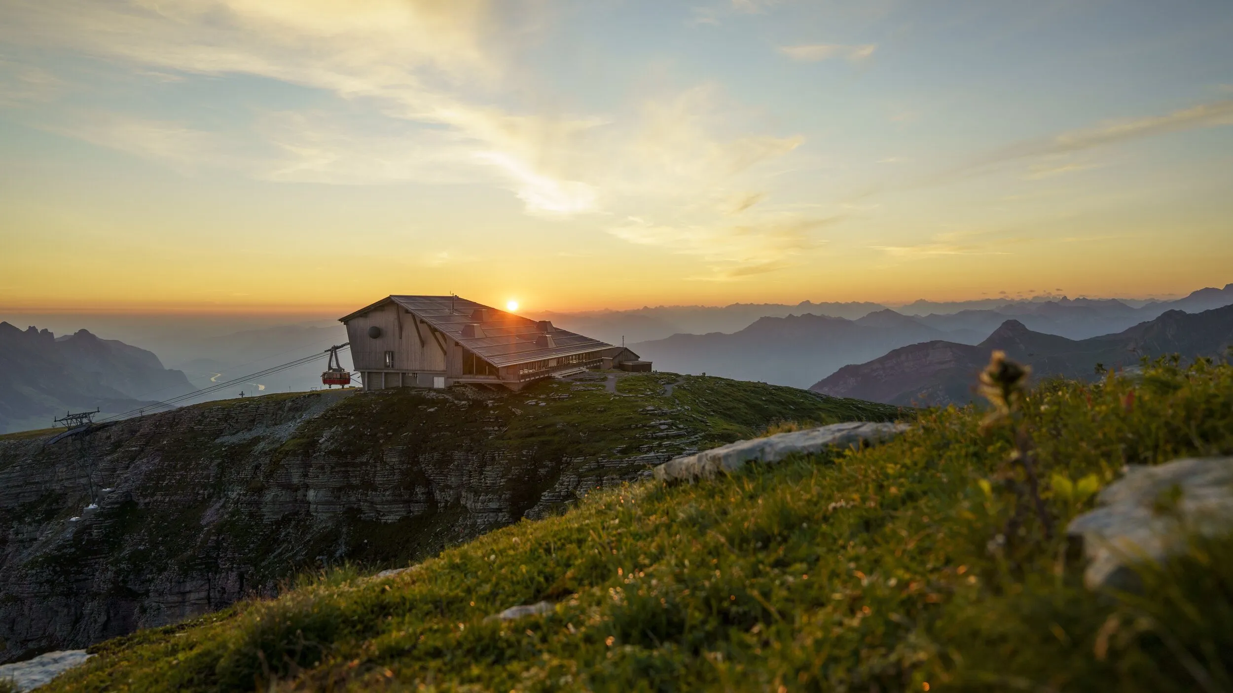 Das Gipfelgebäude auf dem Chäserrugg im Sonnenaufgang, die Luftseilbahn fährt gerade ein