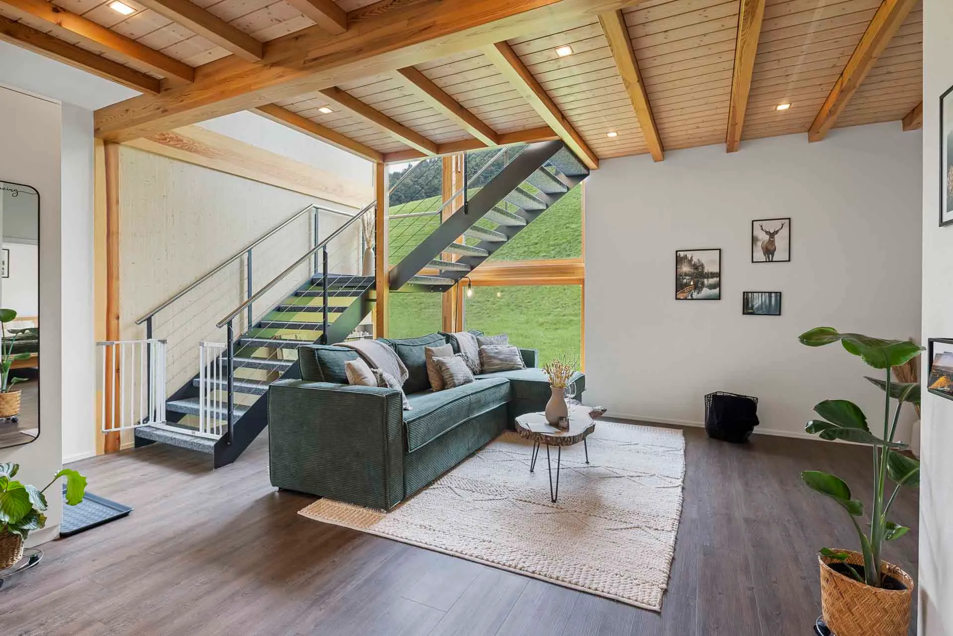 Living room with a green sofa and open stairs to the gallery level