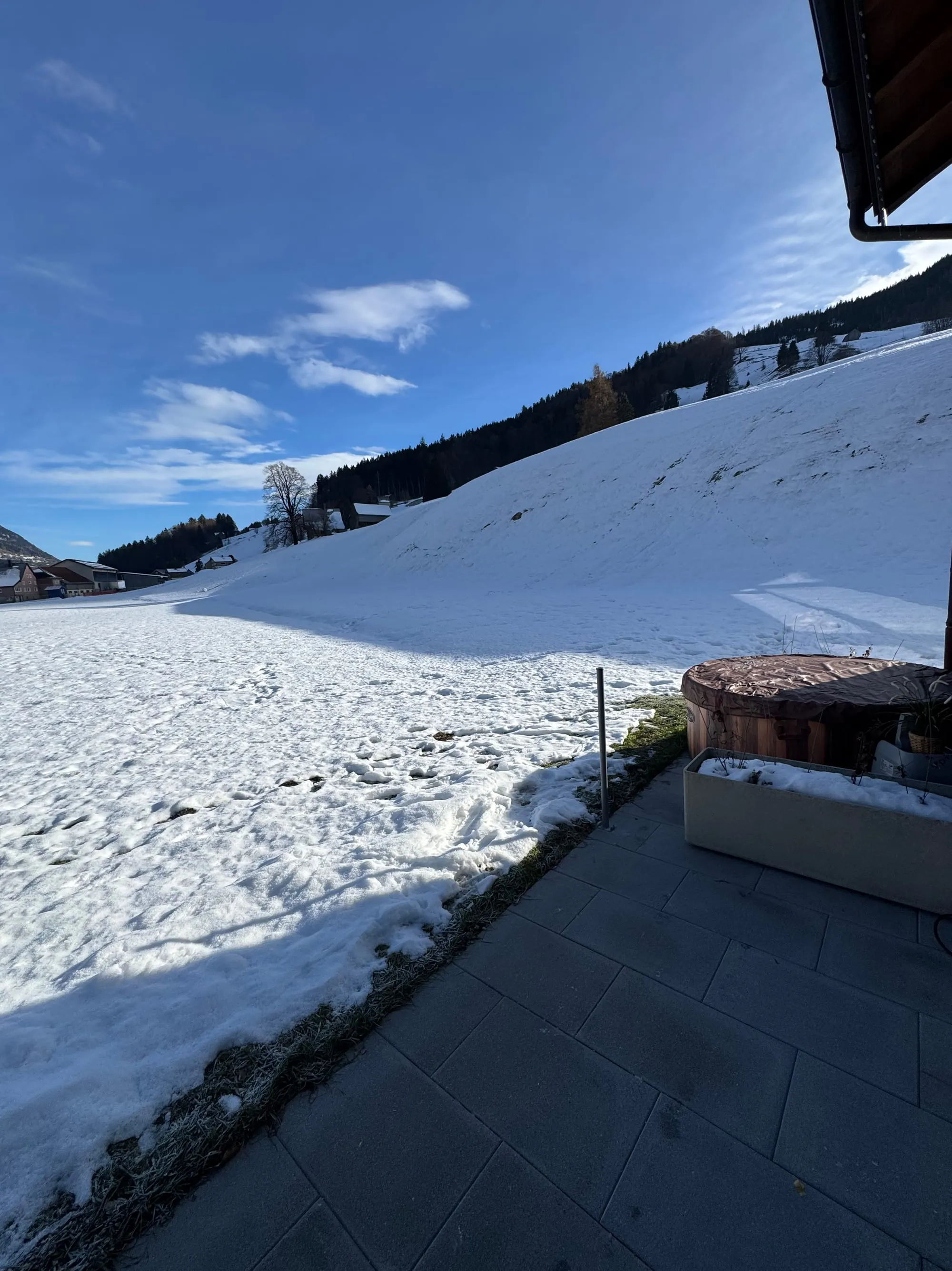 Der winterliche Whirlpool auf der Terrasse mit Blick auf die verschneite Landschaft